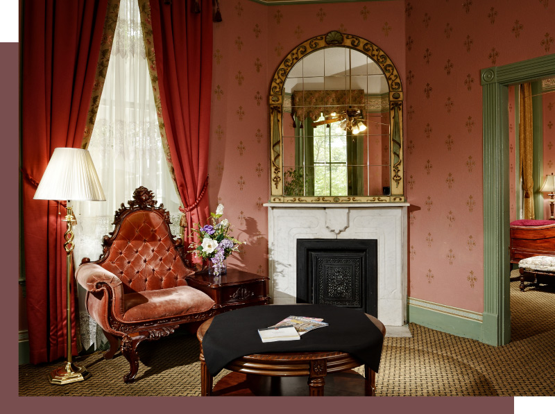 A beautiful window, plush armchair  and fireplace in one of the Crescent's suites.